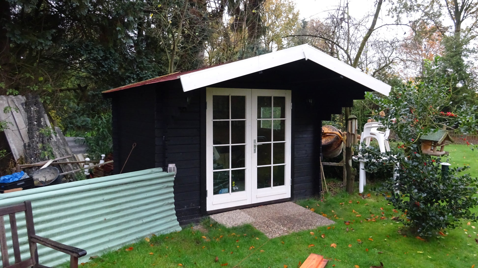 Zwart tuinhuis Interflex 3032 met witte deuren naast vijver en groene tuin