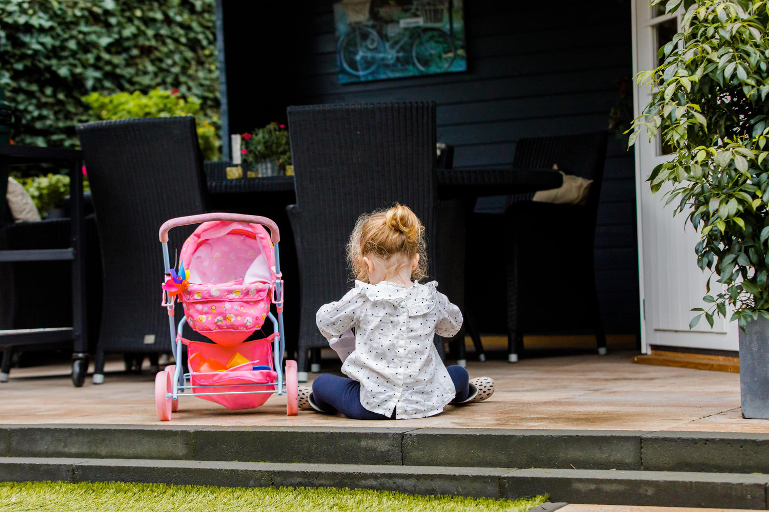 Klein meisje dat speelt op het terras bij een Interflex tuinhuis in de tuin