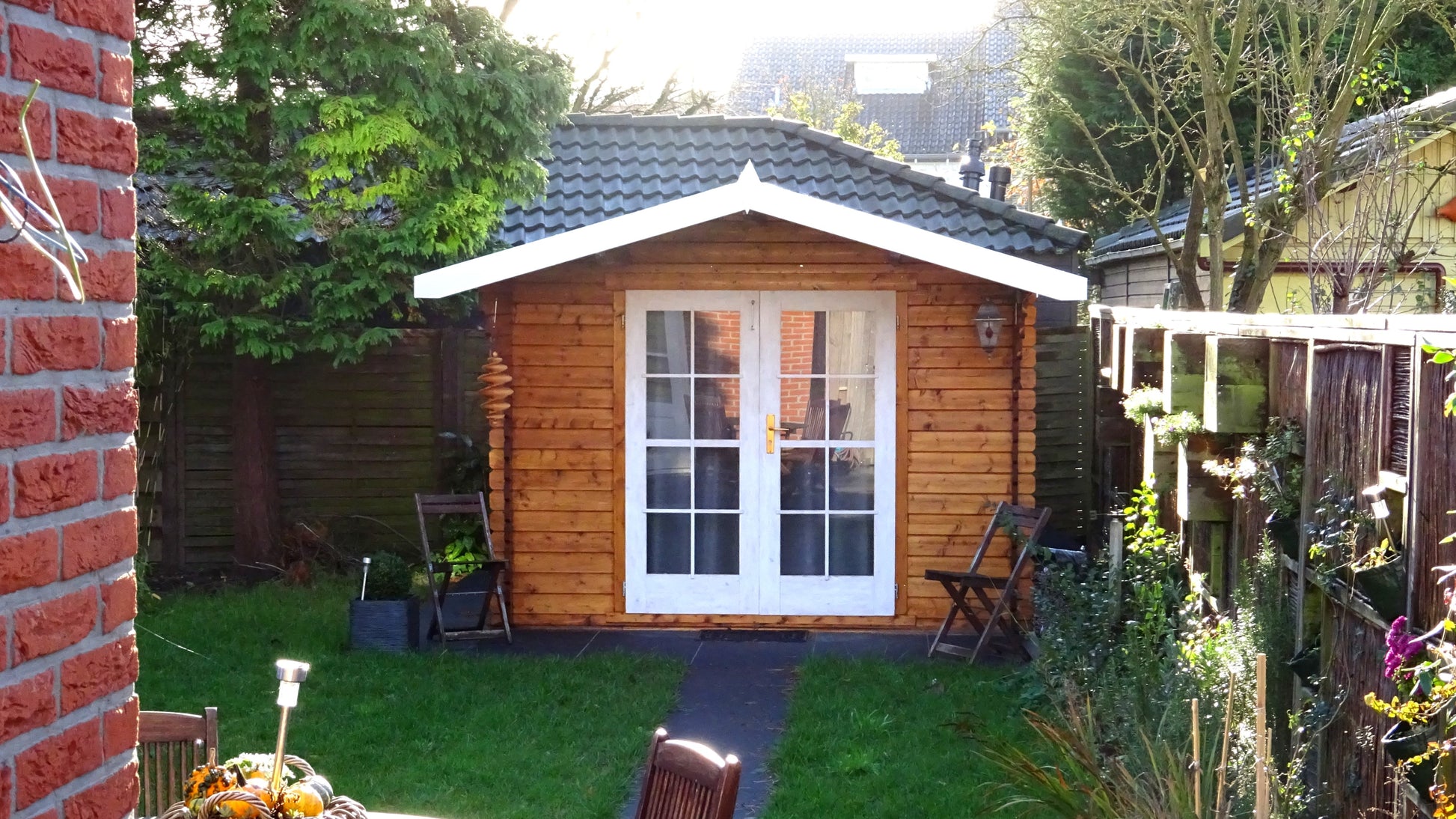 Tuinhuis Interflex 3032 met luifel in oranje houtkleur op grasveld in achtertuin