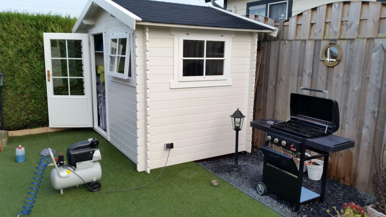 Tuinhuis Interflex 3020 in moderne achtertuin naast schutting met barbecue en zitje op kunstgras