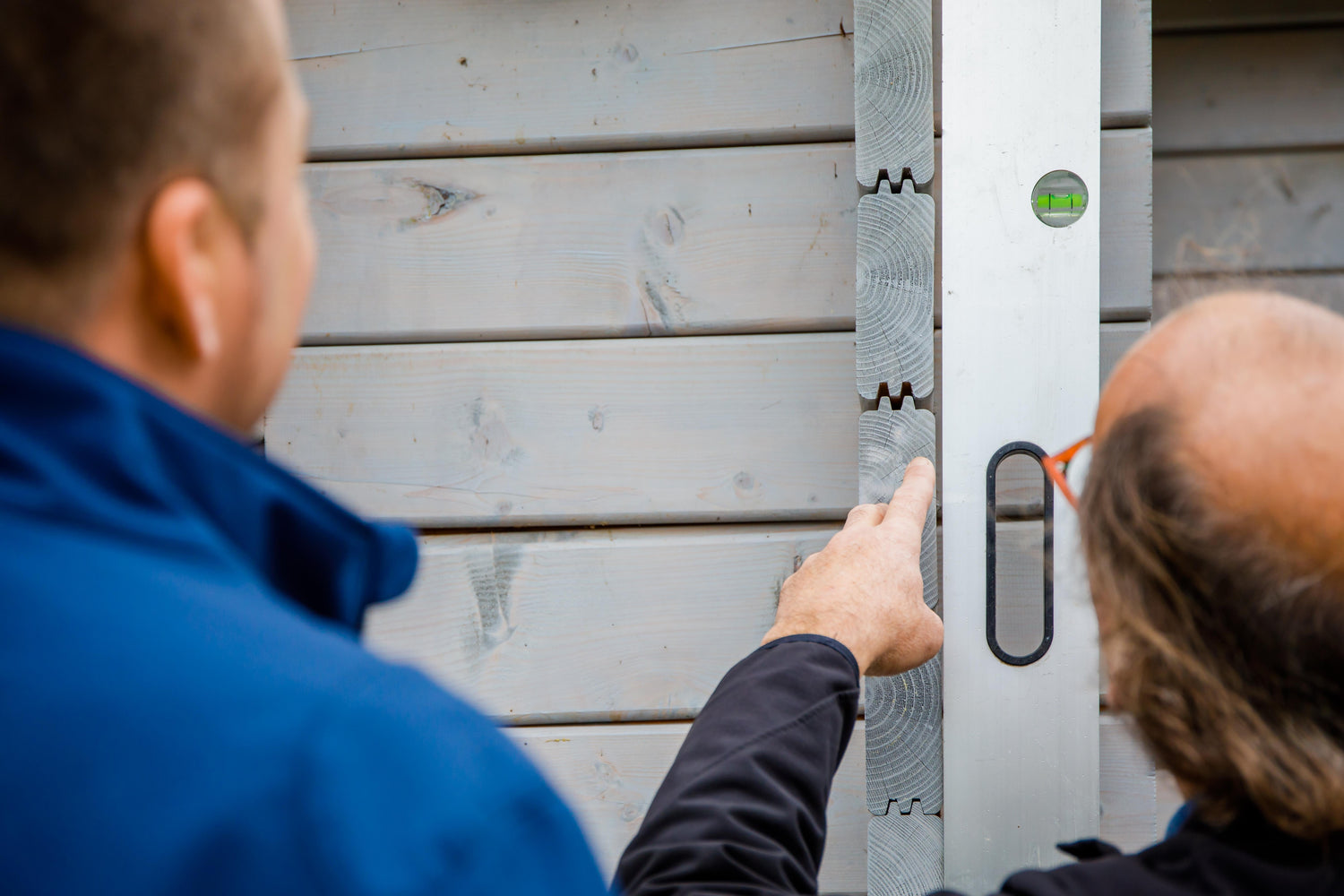 Vakman die de uitlijning van een Inteflex tuinhuiswand controleert met waterpas